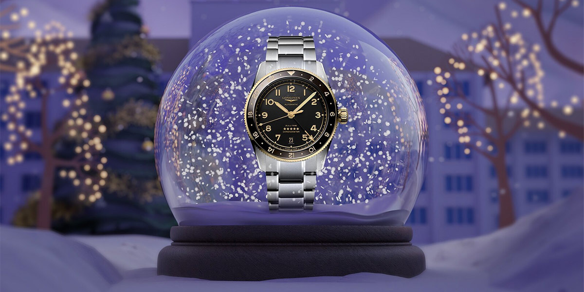 Tissot klocka som du kan köpa som julklapp. Klockan står framför en snöglob och bakgrunden är fylld med snö och ljusslingor. 