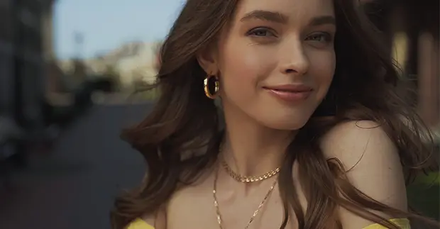 kvinna med halsband och örhängen i guld