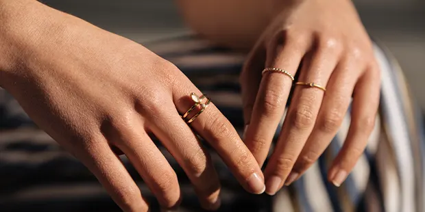 kvinnliga händer med guldringar på flera fingrar