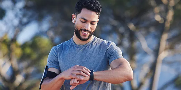 Träningsklockor för män och smartklockor för löpning - man tittar på sin träningsklocka